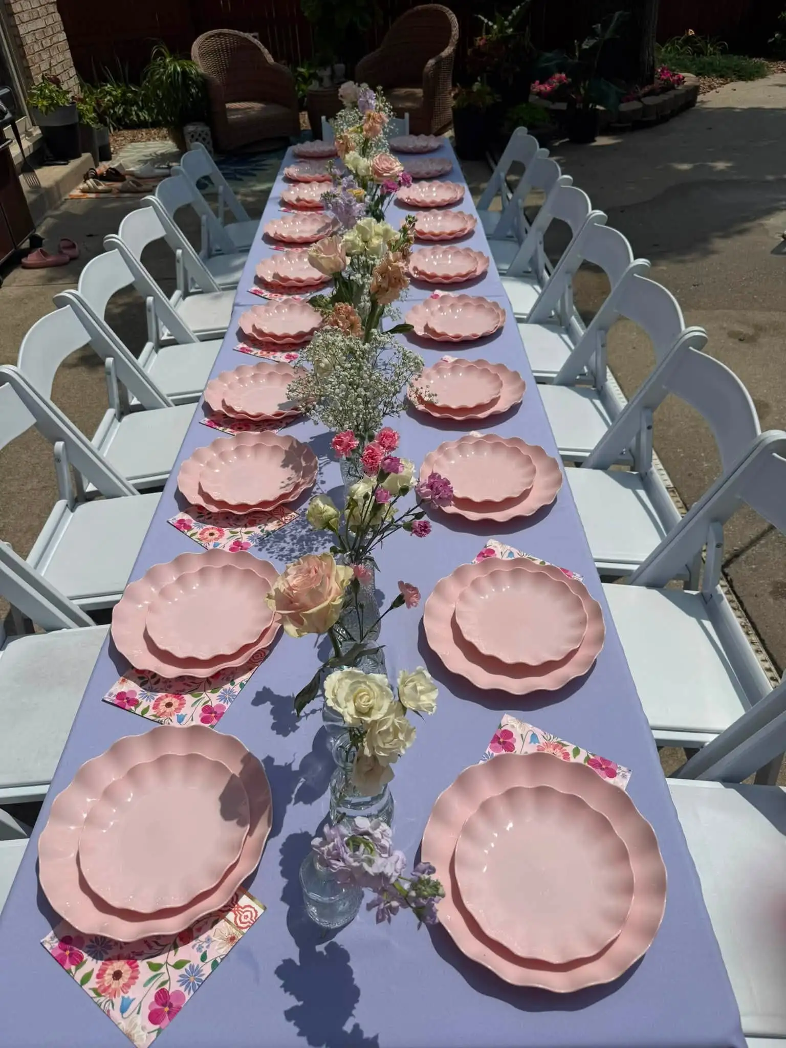 Outdoor tea-party table with pink scalloped plates, floral napkins and bud-vase florals