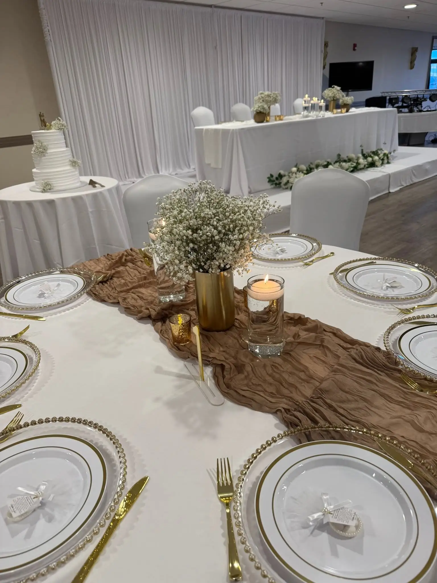 White reception setup with gold-rimmed chargers and a tiered cake — party decorations in Lincoln Park, Chicago