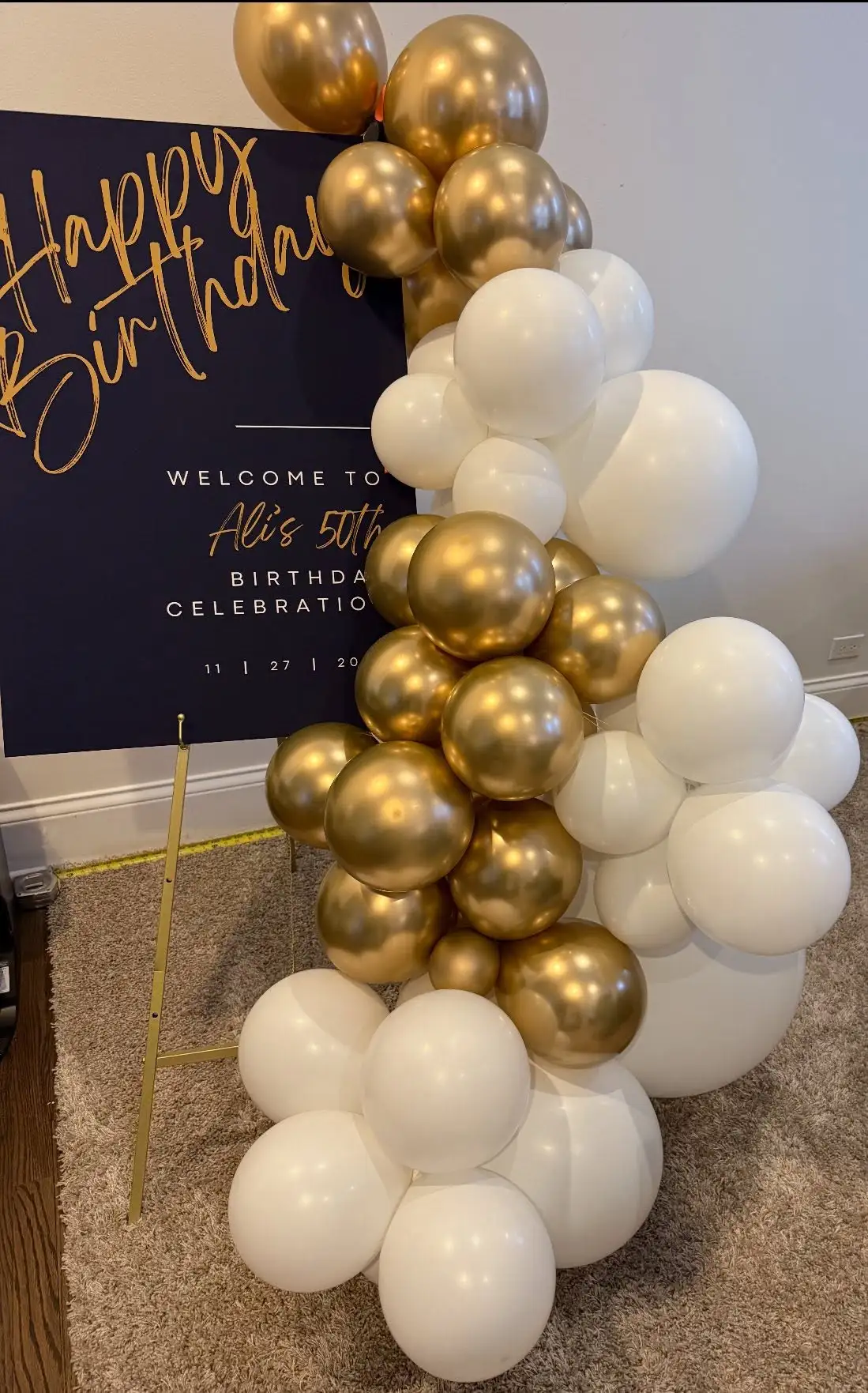 Gold and white balloon garland arranged around a welcome sign for a Chicago party