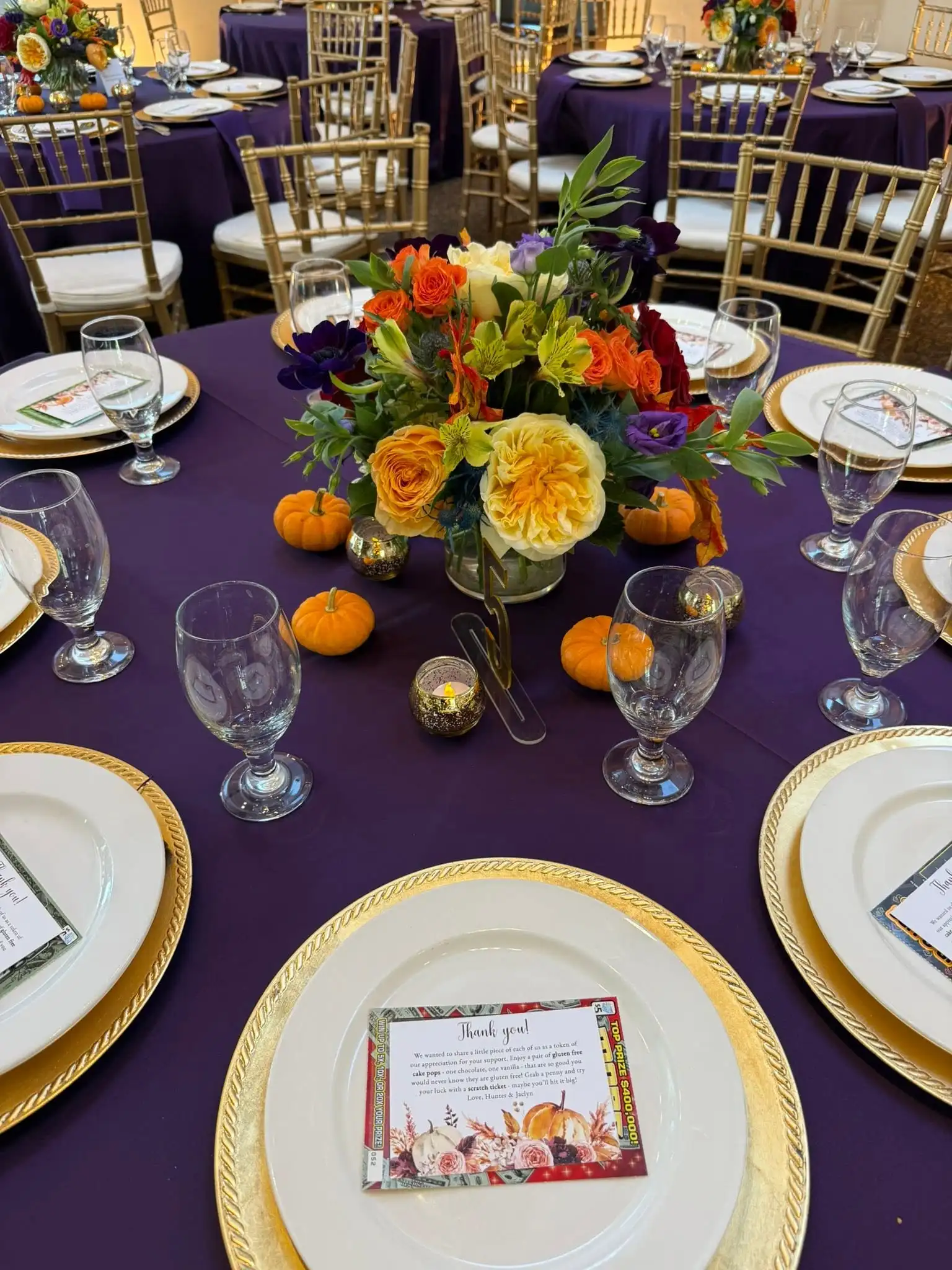 Fall wedding tablescape with deep-purple linens, gold-rimmed chargers and an autumn floral centerpiece